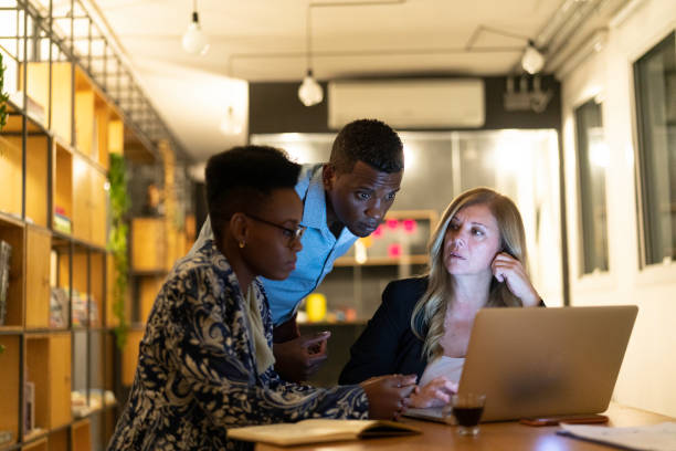 istock Group of coworkers working at night using laptop at modern office 1147777218
