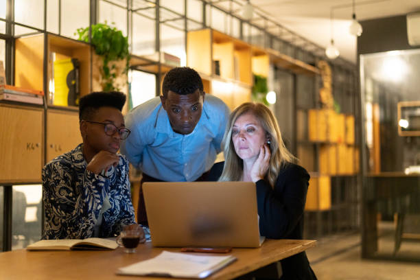 istock Group of coworkers working at night using laptop at modern office 1147777373