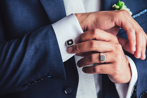 elegant young fashion man fixing cufflinks