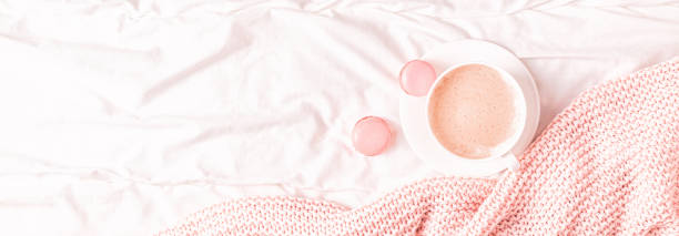 istock Bed with pink knitted plaid, coffee and macaroons 1147780697