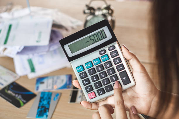 mulher mão segurando calculadora mostrando número défice orçamental para a dívida de cartão de crédito - subtraction - fotografias e filmes do acervo