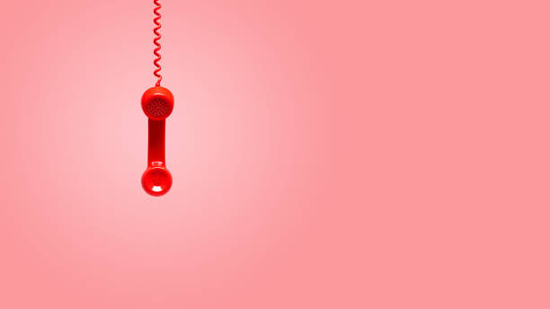 istock Red old telephone receiver hanging on pink background 1147786944