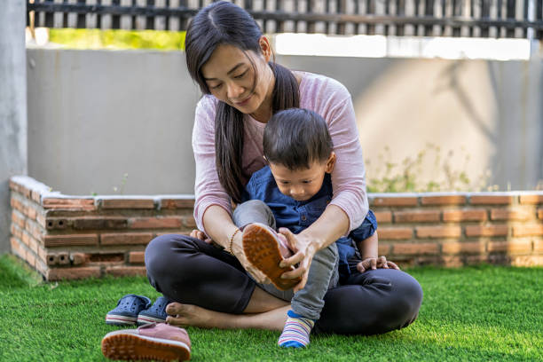 Asian single mom ware shoes to son on the front lawn of modern house for Self learning or home school, Family and single mom concept, selective focus Asian single mom ware shoes to son on the front lawn of modern house for Self learning or home school, Family and single mom concept, selective focus tie game stock pictures, royalty-free photos & images