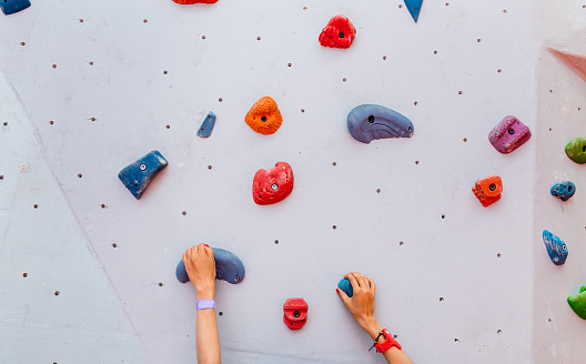 Climber young woman starting bouldering track on artificial wall indoor, hands closeup