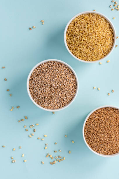 istock Uncooked crushed spelt, wheat and bulgur in a white bowl on pastel blue background 1147794995