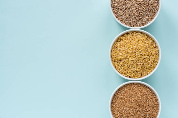 istock Uncooked crushed spelt, wheat and bulgur in a white bowl on pastel blue background 1147795831