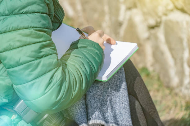 istock Photographer woman writing on notebook at park. 1147796089