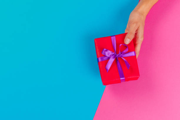 istock Woman holding gift box on color background 1147797638
