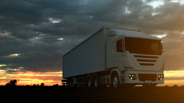 istock Large freight truck driving on a highway at sunset backlit by a bright orange sunburst under an ominous cloudy sky. 3d Rendering 1147799490