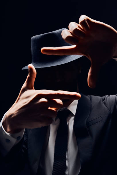istock Faceless man in suit and hat looking through a finger frame 1147802317
