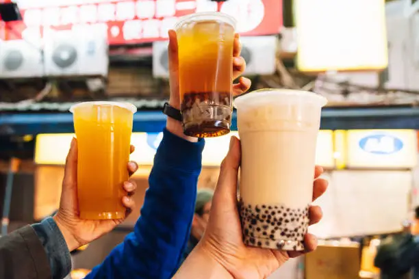 Photo of Tourists put Bubble Milk Teas up in the air, street food at Ximending in Taipei, Taiwan.