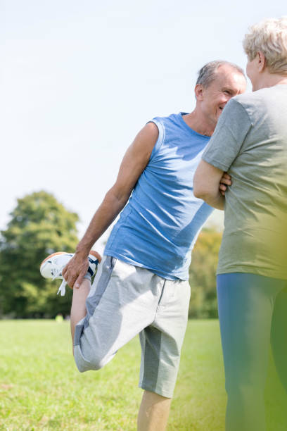 istock Senior man exercising while woman standing in park 1147804748