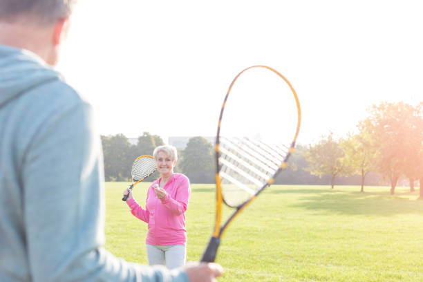 istock Smiling senior woman serving badminton in park 1147804817