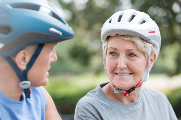 istock Senior woman wearing cycling helmet while looking at man 1147804875