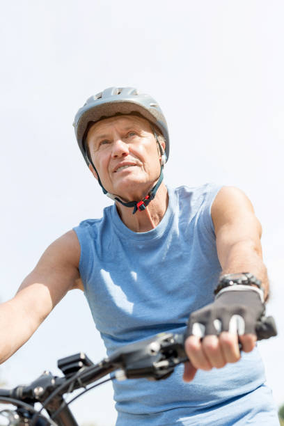 istock Low angle view of determined senior man cycling against sky 1147805112