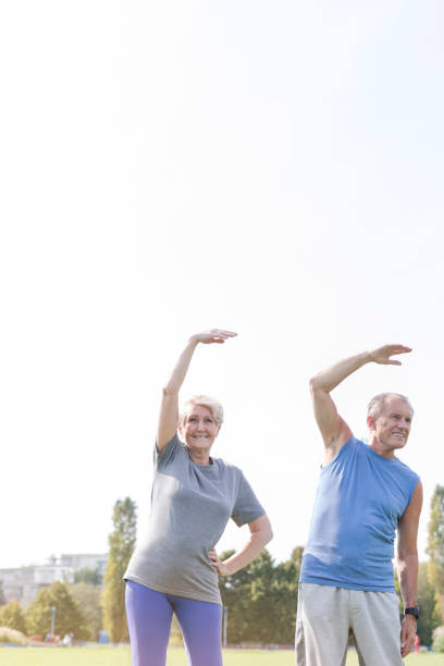 istock Senior couple doing stretching exercise in park against sky 1147805187