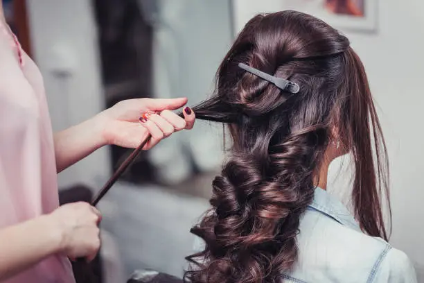 Closeup of a hairdresser coiffeur makes beauty hairstyle.