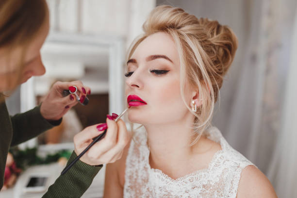 Professional stylist doing make-up for blonde woman
