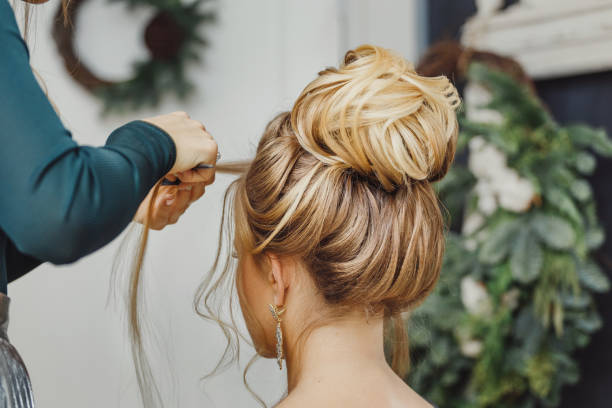 Hairdresser makes complex and beautiful hairstyle upper bun. Suitable for evening and wedding style Hairdresser makes complex and beautiful hairstyle upper bun. Suitable for evening and wedding style hair bun stock pictures, royalty-free photos & images