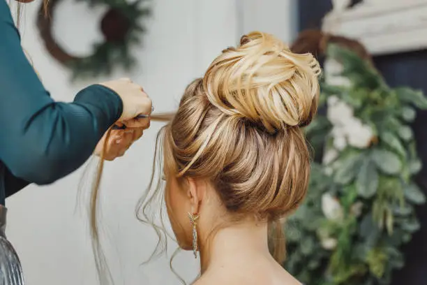 Photo of Hairdresser makes complex and beautiful hairstyle upper bun. Suitable for evening and wedding style