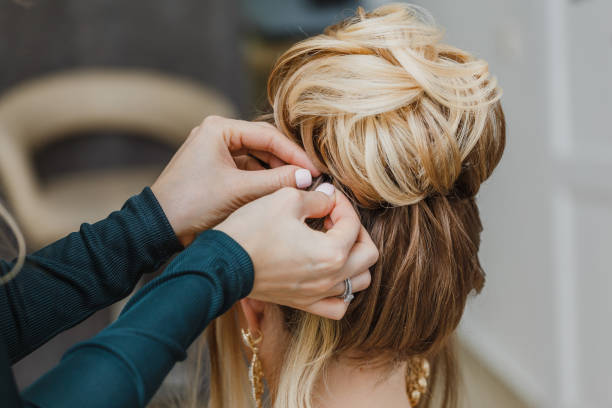 Hairdresser makes complex and beautiful hairstyle upper bun. Suitable for evening and wedding style Hairdresser makes complex and beautiful hairstyle upper bun. Suitable for evening and wedding style bridal hair stock pictures, royalty-free photos & images