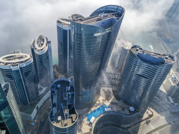 Top aerial view shot of skyscrapers in the city with fog clouds passing by - Abu Dhabi Al Reem island towers