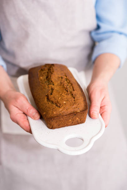istock Women's hands holding freshly baked cake, bread with grains and seeds. 1147817852