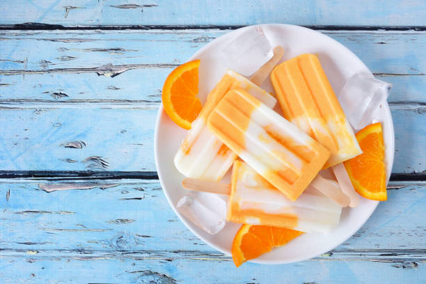 istock Plate of orange yogurt popsicles over rustic blue wood 1147819050