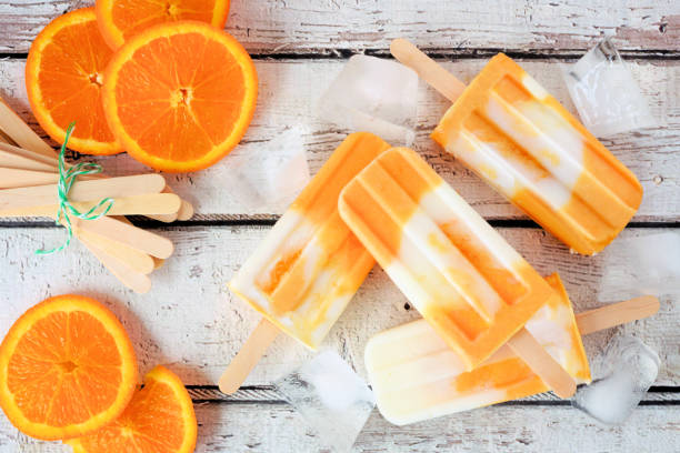 istock Orange yogurt popsicles, top view scattered on white wood 1147819267
