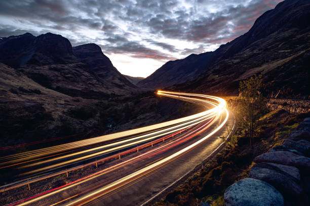Light trails in the night on a remote road in mountains Light trails in the night on a remote road in mountains, Highlands, Scotland, UK. light trail photos stock pictures, royalty-free photos & images