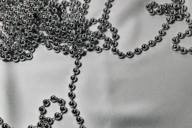 istock Beautiful round silver beads and beads on white fabric background. Glossy shiny grey surface. Modern jewelry 1147822586