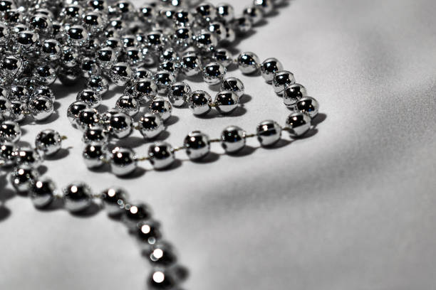 istock Beautiful round silver beads and beads on white fabric background. Glossy shiny grey surface. Modern jewelry 1147822598
