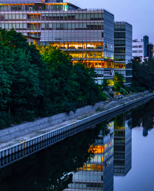 der teltowkanal in berlin-tempelhof mit blick auf ein modernes bürogebäude. einige etagen sind bunt beleuchtet. diese beleuchtung kann man als reflexionen im wasser sehen. - teltow stock-fotos und bilder