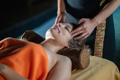 Beautiful Latin American woman relaxing with a massage at the spa - beauty concepts