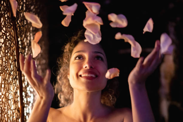 mujer beutiful en el spa lanzando pétalos en el aire - flower toss fotografías e imágenes de stock