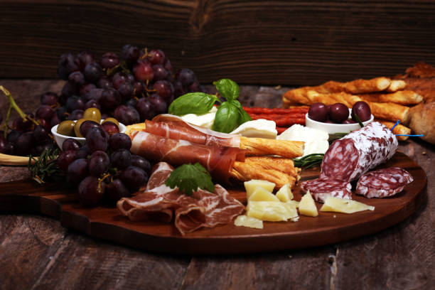 istock antipasto various appetizer. Cutting board with prosciutto, salami, cheese, bread and olives on dark wooden background 1147830394