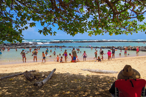 Wailua, Kauai, Hawaii, USA - 07/08/2015: Man relaxing in the shade watching beach fun at  Lydgate Beach Park