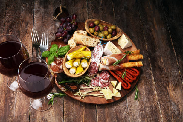 istock antipasto various appetizer. Cutting board with prosciutto, salami, cheese, bread and olives on dark wooden background 1147831760