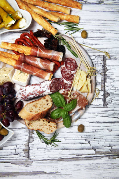 istock antipasto various appetizer. Cutting board with prosciutto, salami, cheese, bread and olives on white wooden background 1147833614