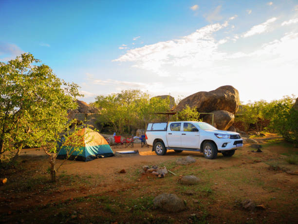Namibia Damaraland camping ground Namibia Damaraland camping ground with a raised tent and a white 4x4 in the foreground. toyota hilux stock pictures, royalty-free photos & images