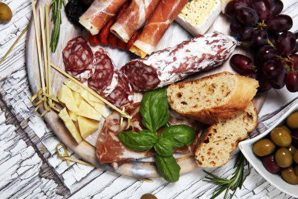 istock antipasto various appetizer. Cutting board with prosciutto, salami, cheese, bread and olives on white wooden background 1147835803