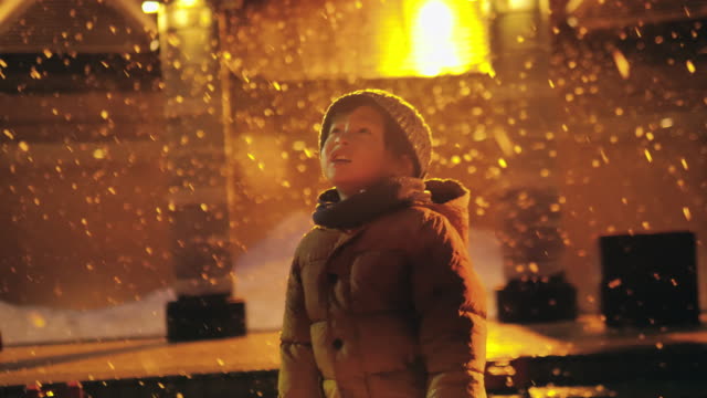 Cheerful asian child playing in the snow at night.