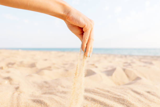 istock Female hand pours sand on beach. 1147837674