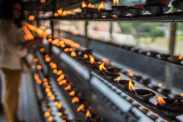 Ritual oil lamps in clay saucers burn in honor of Buddhist tradition of a gift of fire.
