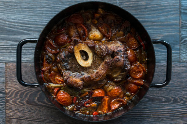 Cooked Osso Buco Veal Shanks with Vegetables in Cast-Iron Pot on Wooden Background Cooked Osso Buco Veal Shanks with Vegetables in Cast-Iron Pot on Wooden Background ossobuco stock pictures, royalty-free photos & images