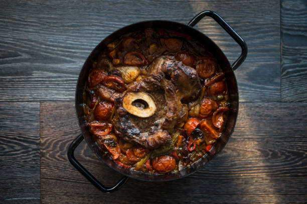 Cooked Osso Buco Veal Shanks with Vegetables in Cast-Iron Pot on Wooden Background Cooked Osso Buco Veal Shanks with Vegetables in Cast-Iron Pot on Wooden Background ossobuco stock pictures, royalty-free photos & images