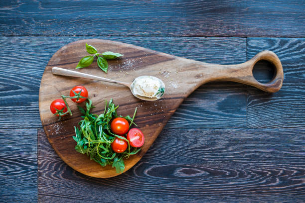 Fresh Ingredients, Tomato, Rocket, Basil and Herbs, on Wooden Board for Making Perfect Mediterranean Dish