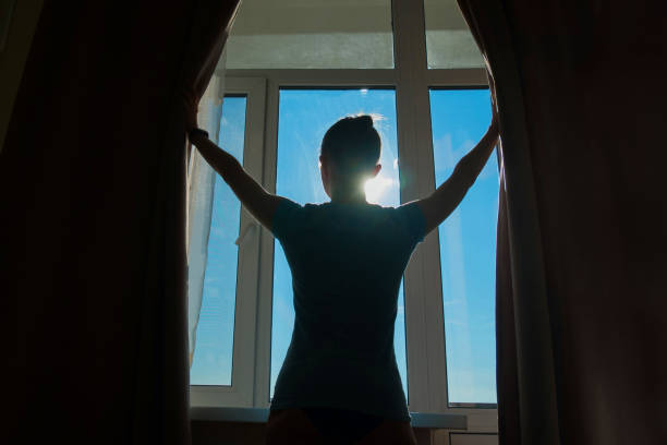 istock Woman opening window curtains 1147841903