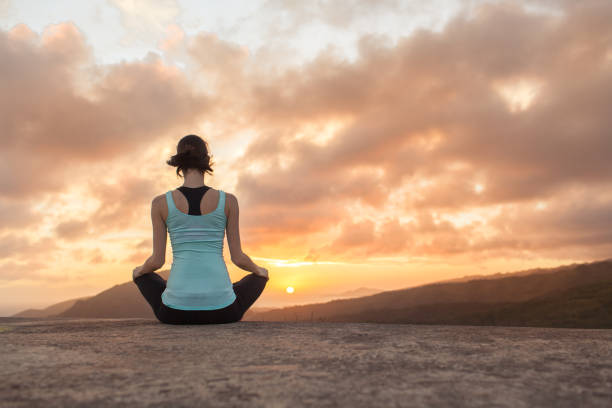 istock Young woman meditating from a mountain top facing beautiful sunset. 1147846999