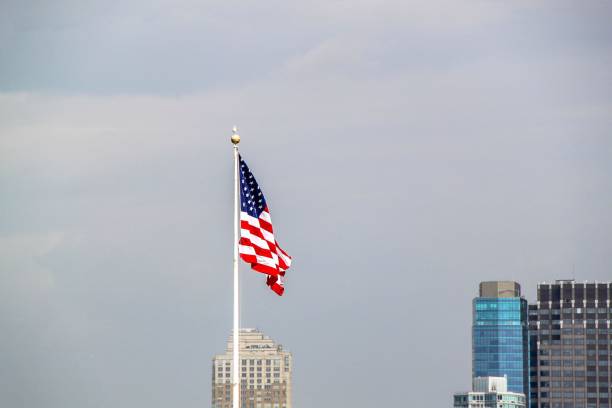 istock American flag on sky and Manhattan on background. 1147847243